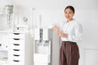 © Pixel-Shot - Young Asian businesswoman with glass of water near cooler in office
