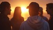 © Thares2020 - Group of friends silhouetted against a vibrant sunset engaged in discussion outdoors