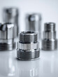 © Mikhail Vorobev - Shiny metallic threaded pipe connectors with reflective surfaces arranged on a smooth white background showing industrial plumbing components in soft focus depth