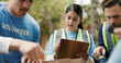 © Davids25/peopleimages.com - Clipboard, volunteer or people with paper bag in park, community service or packaging for charity drive. Teamwork, non profit or woman with donation list for food security crisis, supplies or outdoor