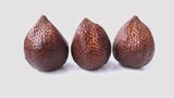 Three salak or snake fruit. Three salak fruits (Salacca zalacca) displayed against a plain background. Each fruit features a distinctive reddish-brown scaly skin, resembling snake scales