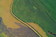 © Andrii Chagovets - Top-down aerial photograph showing a sharp, curved boundary between two contrasting fields: vibrant green crop and light brown farmland. Represents agricultural land use and abstract patterns.