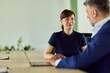 © bnenin - Professional Woman and Man in Office Discussing at Laptop Desk in Modern Workspace