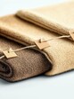 © ratna - Close-up of stacked, folded knitted fabric in natural earthy tones, with small square tags attached by twine.