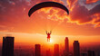 © Oran - Person paragliding against vibrant sunset, showcasing thrilling adventure sky above city skyline. scene captures beauty of freedom and excitement