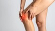 © Indar - Legs and hands of a person experiencing knee pain, digitally highlighted in red against a solid, light grey background