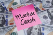 © Reza - A clear message of Market Crash on a pink sticky note atop scattered hundred-dollar bills, illustrating a severe economic downturn and financial instability