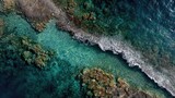Aerial view of turquoise sea around a coral reef with white waves breaking on a rocky shoreline. Concept Turquoise sea, Coral reef, Aerial view, White waves breaking, Rocky shoreline