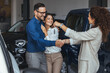 © Dragana Gordic - Joyful Couple Shakes Hands With Car Dealer After Vehicle Purchase at Showroom