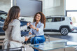 © Dragana Gordic - Smiling Saleswoman Hands Car Keys To Customer In Showroom During Vehicle Exchange Today