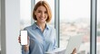 © Vasiliy - Confident businesswoman holding a laptop and showing a smartphone with a blank white screen. Professional woman in a modern office presenting a mobile device for mockup