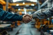 © CojanAI - Two adults shaking hands in a factory setting expressing agreement