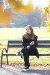 © Yevhen - Girl is sitting on a bench in city autumn park with paper cup of coffee