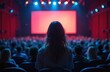 © Maryna - Woman watches movie premiere in magenta cinema auditorium with lively crowd. Spectators enjoy film screening in dark theatre. Audience sits in seats, focused on bright screen.
