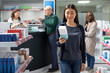 © DC Studio - Asian woman customer inspecting pills and vitamins in a pharmacy shop, reading boxes labels for guidance about dosage. Professional pharmaceutical care for wellness and self care.