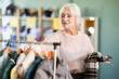 © JackF - Mature woman chooses fashionable coat or jacket in a clothing store