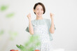 © kapinon - エプロン姿の主婦がキッチンで野菜料理を準備しながらガッツポーズする笑顔の女性　家庭でのダイエットや健康的な食生活のシーン