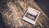 Vintage polaroid photo resting on a rustic wooden surface with a nostalgic film grain effect. lifestyle magazines.