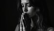 © Vadym - Woman clasps hands praying or meditating. She looks down with closed eyes, hair falls around her face in dim light. Deep personal reflection, quiet mood.