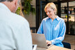 © Westend61 - Smiling employee working with laptop at desk during office meeting