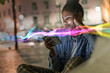 © Westend61 - Smiling woman using mobile phone with glowing effects at night outdoors