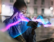 © Westend61 - Smiling woman using mobile phone with glowing effects at night outdoors