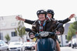 © Westend61 - Smiling couple riding scooter outdoors having fun together