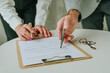 © Westend61 - Closeup of realtor and client signing real estate contract on table