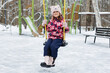 © Studio Peace - Caucasian girl smiling at camera while sitting on swing in snowy playground during winter.