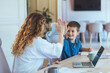 © Dragana Gordic - Mom And Son Share High Five At Modern Home Office Desk With Laptop And Notebooks