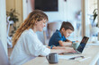 © Dragana Gordic - Mom Works on Laptop While Son Draws at Home Desk During Quiet Family Morning