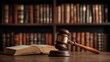 © Артур Комис - A wooden gavel rests on a desk in front of a large, blurred bookshelf filled with legal volumes