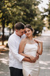 © shchus - Wedding photography, portrait of happy smiling newlyweds, stylish groom and beautiful young brunette bride, tenderly hugging outdoors on the street in the city, in the park.