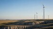 © antuanetto - Wind turbines on eroded landscape under clear blue sky representing ecology
