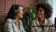 © Viktor - Two women wearing headphones laugh together. In recording studio with microphone between. Setting suggests podcast radio show recording session. Both women smiling, engaged in conversation.