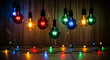 © PhotoArtHub - Group of colored electric bulbs, hanging against wood background. A string of tiny bulbs below. Representative of celebration, festive mood, party, holiday