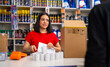 © oscargutzo - Woman employee processing transaction for customer at retail store checkout counter