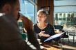 © Marko Geber - Senior woman consulting with adult colleague at cafe, engaged