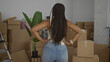 © Krakenimages.com - Woman in jeans and tank top with hands on hips amid stacked cardboard boxes in house; moving new home confidence.