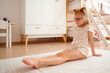 © khmelev - Young girl doing floor yoga stretch at home
