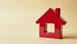 © Denis - Glossy red ceramic figurine shaped like a house with a small cutout window against a light beige background