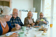 © Davor - Senior friends sharing a cheerful lunch at home
