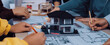 © InfiniteFlow - A dynamic group engaged in architectural planning, featuring hands working on blueprints with a model house at the center, showcasing teamwork and creativity in design. SACTR