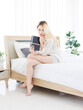 © Bangkok Click Studio - Asian beautiful attractive happy young woman blonde long hair wearing white shirt sitting on cozy bed soft natural light bedroom posing holding book peaceful weekend morning at home lifestyle concept.