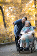 © kapinon - 落ち葉の中秋の屋外で介護する女性と車椅子の高齢者、訪問介護や散歩などの外出イメージ　指を差す見つめるシーン　全身