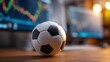 © The Little Hut - Soccer ball with financial charts background displaying stock market data, business concept image