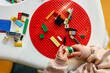 © shine.graphics - Child's hands playing with colorful building blocks on a red baseplate