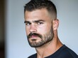 © Sam - A focused young man with a stylish beard and short hair gazes confidently at the camera, showcasing determination.