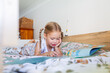 © Austockphoto - Little preschool aged child lying on bunk bed reading a storybook looking at pictures in bedroom
