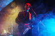 © New Africa - Man playing electric guitar on stage with smoke, low angle view